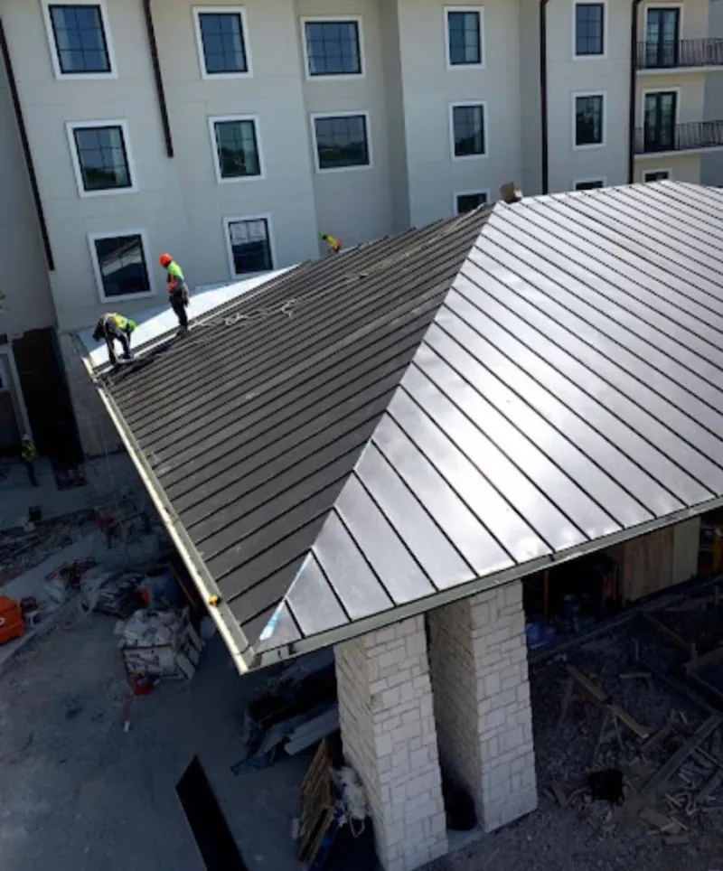 Crew installing standing seam metal roof panels on a commercial project in McAllen